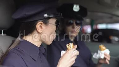 <strong>值班</strong>女警察在巡逻车上吃汉堡，饮食不健康